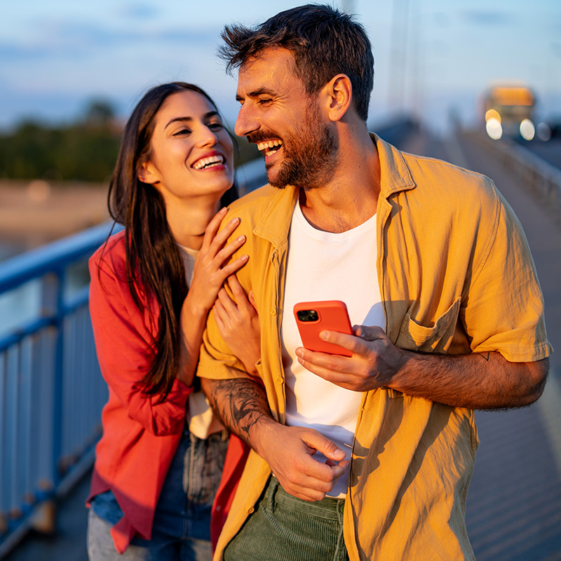 Laughing couple on a bridge at sunset